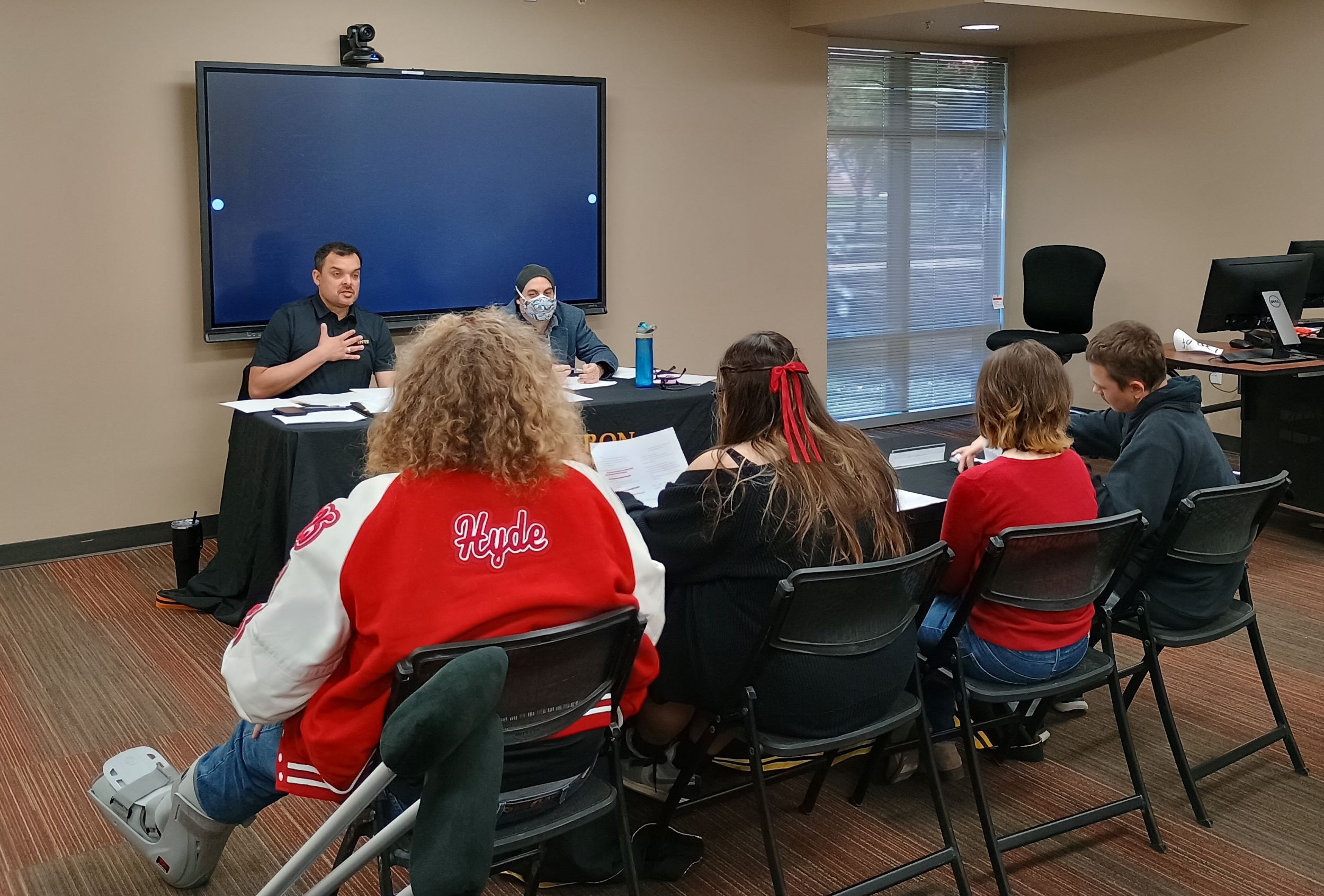 Four high school students sit across Professors Edris Montalvo and William Doug Catterall to defend their prepared thesis.